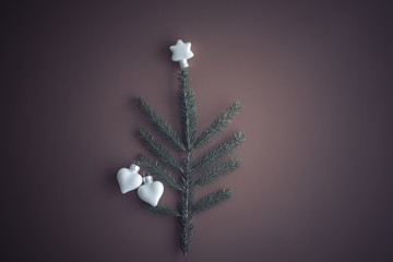 Art Christmas Greeting Card. Christmas tree white glass toys two hearts and natural fir branch of spruce on red paper.