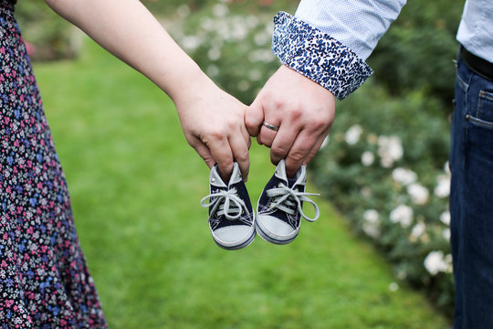 Eltern halten Babyschuhe mit den Fingern