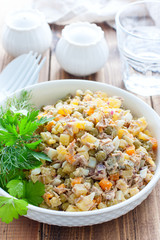 Russian traditional salad Olivier with vegetables and meat. Winter saladHomemade salad Olivier with boiled meat and meat on a wooden table, selective focus