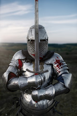 Knight in armor and helmet poses with sword
