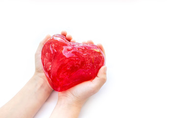 Modern toy called slime. Heart made of transparent red slime. Hands holding a mucus isolated on a white background.	