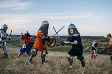 Knights in armour and helmets fight with swords