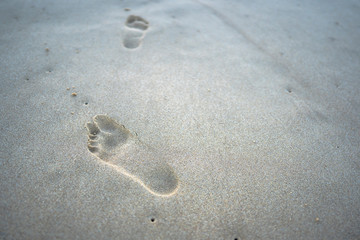 Fototapeta na wymiar step of foot print walking on the sea beach for travel therapy concept 