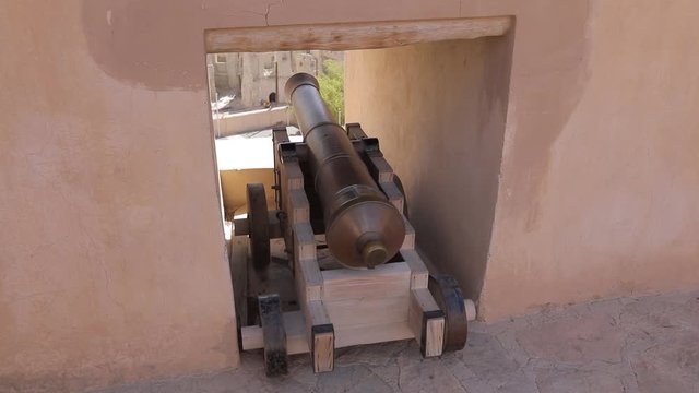 Nizwa Fort, Oman - February 2019. Traditional Omani fortress, general plan and details, guns and a flag on the main tower. Panorama around the big gun in the fortress.