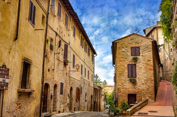 Fototapeta na wymiar Old cozy street in in old town of San Gimignano, Tuscany, Italy. San Gimignano is typical Tuscan medieval town in Italy