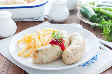 Homemade sausages with chicken and french fries on a white plate, horizontal