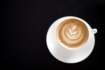 Cappuccino on black background with beautiful coffee art. Cup of Coffee with milk.