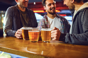 Friends with glasses of beer in hand at the bar.