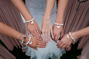Four woman's hand with heart bracelet - obrazy, fototapety, plakaty