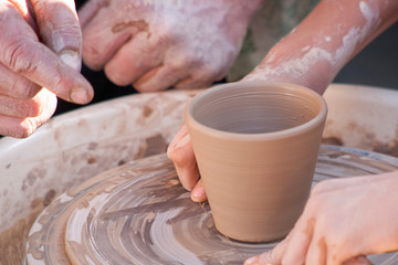 A potter craftsman transfers his skills to a student