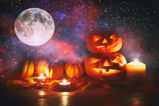 holidays image of halloween. Pumpkins over wooden table at night scary, haunted and misty forest