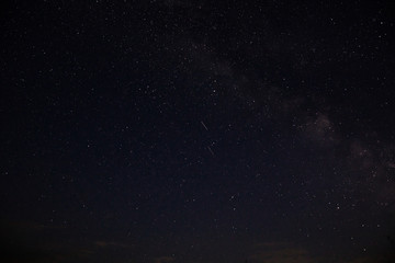Amazing starry night sky above lake in mountains. Beautiful night sky with Milky Way and falling stars. Breathtaking landscape. View on sky from camp tent