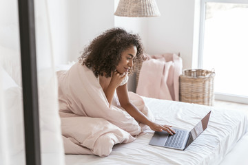 Cheerful international young woman working at computer