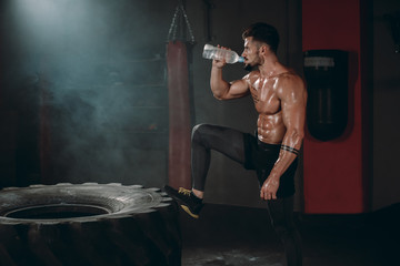 Thirsty fit body man after a cross fit workout drinking some water from a plastic bottle