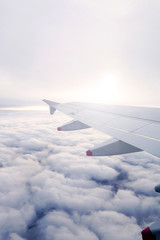 Fototapeta premium the wing of the aircraft, it is a solar flare, flying over the beautiful clouds on the plane, vertical photo
