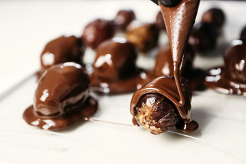 Dates in chocolate, dessert. Confectioner pours chocolate over dessert. Macro, close-up.