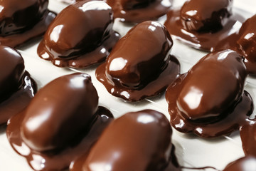 Dates in chocolate, dessert. Confectioner pours chocolate over dessert. Macro, close-up.