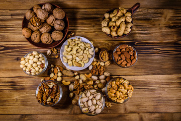 Obraz na płótnie Canvas Various nuts (almond, cashew, hazelnut, pistachio, walnut) in bowls on a wooden table. Vegetarian meal. Healthy eating concept. Top view