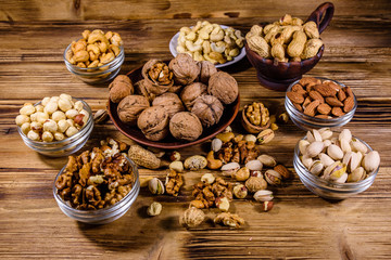 Various nuts (almond, cashew, hazelnut, pistachio, walnut) in bowls on a wooden table. Vegetarian meal. Healthy eating concept
