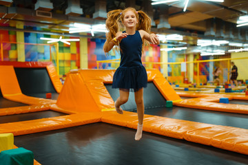 Adorable little girl bouncing on kids trampoline - obrazy, fototapety, plakaty