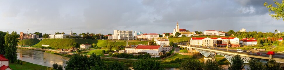 Fototapeta na wymiar Panoramic view of the city of Grodno, the embankment, the Neman river and the old city. Autumn evening, the city in the sunshine on a background of dark clouds.
