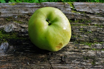 A green apple lies on an old board. Macro. Russia.