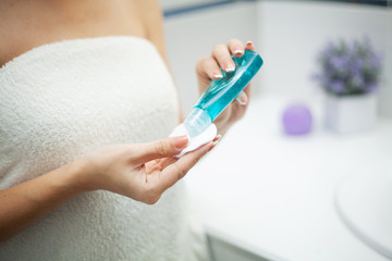 Skin care. Woman use skin care products at home in light bathroom