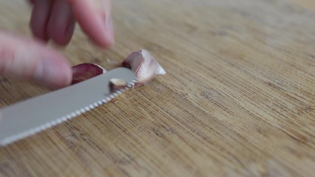 Peeling fresh garlic on a wooden chopping board