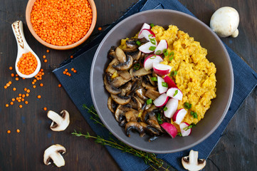 Lentil porridge with mushrooms, radish in a bowl on a dark background. Dietary, lean menu. Vegetarian dish. Top view.