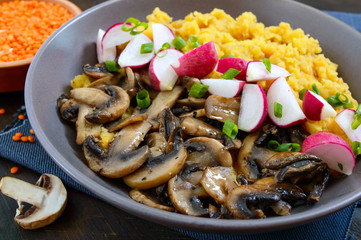 Lentil porridge with mushrooms, radish in a bowl on a dark background. Dietary, lean menu. Vegetarian dish