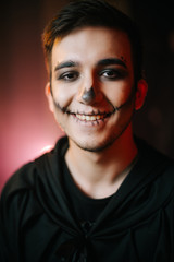 Young man with Halloween make-up smiling at the camera. A close-up of a happy man's face