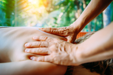 Acupressure massage in spa centre outdoor. Woman at acupressure back massage, masseur's hands close up. Body therapy for healthy lifestyle. - obrazy, fototapety, plakaty