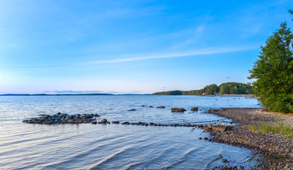 Long Exposure of Sunset at the Paijanne lake. Beautiful scape with stone beach, pine forest and water. Lake Paijanne, Finland.