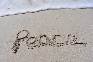 Close up background  with peace written in the sand with ocean wave foam