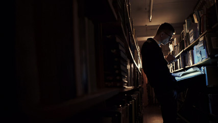 Person with gloves looking at papers in the dark