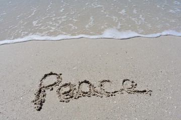 Horizontal background with peace written in the sand with a ocean wave