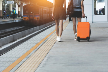 Fototapeta na wymiar Woman dragging orange suitcase luggage bag, walking in train station. Travel concept.