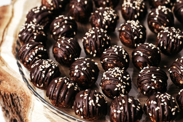 Round chocolates candy with sesame seeds. Dark background, luxury dessert, dark chocolate, handmade.