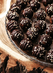 Round chocolates candy with sesame seeds. Dark background, luxury dessert, dark chocolate, handmade.