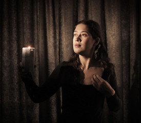 dark key portrait of a young woman with canldle light close up indoor photo