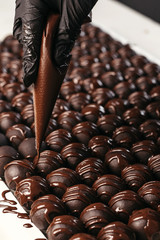 Round chocolates candy. Dark background, luxury dessert, dark chocolate, handmade. Vertical photo.