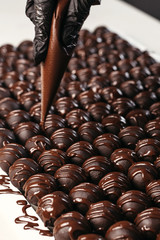 Round chocolates candy. Dark background, luxury dessert, dark chocolate, handmade. Vertical photo.