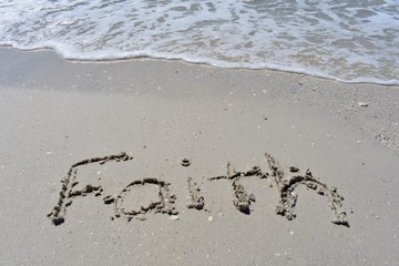 Horizontal background of faith written in sand on the beach