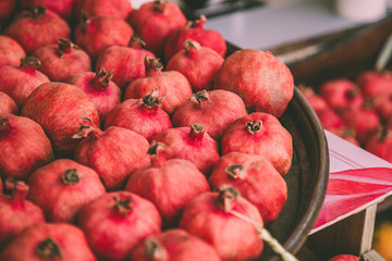Ripe juicy red pomegranates on the wooden shelf. Harvest and sell of organic fresh fruits.
