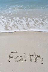 Vertical background of faith written in sand on the beach