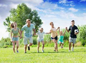 Smiling mother and father with four kids  on green lawn