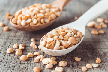 Dry yellow peas in a wooden spoon on old boards. Chipped yellow peas are used for cooking.