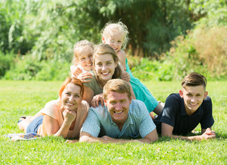 Naklejka na ściany i meble Portrait of big happy family with parents and four children on green lawn outdoors