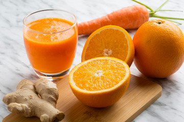 Healthy orange, carrot and ginger juice. Composition on white marble background seen from above.