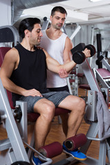 Man during training with  instructor in gym